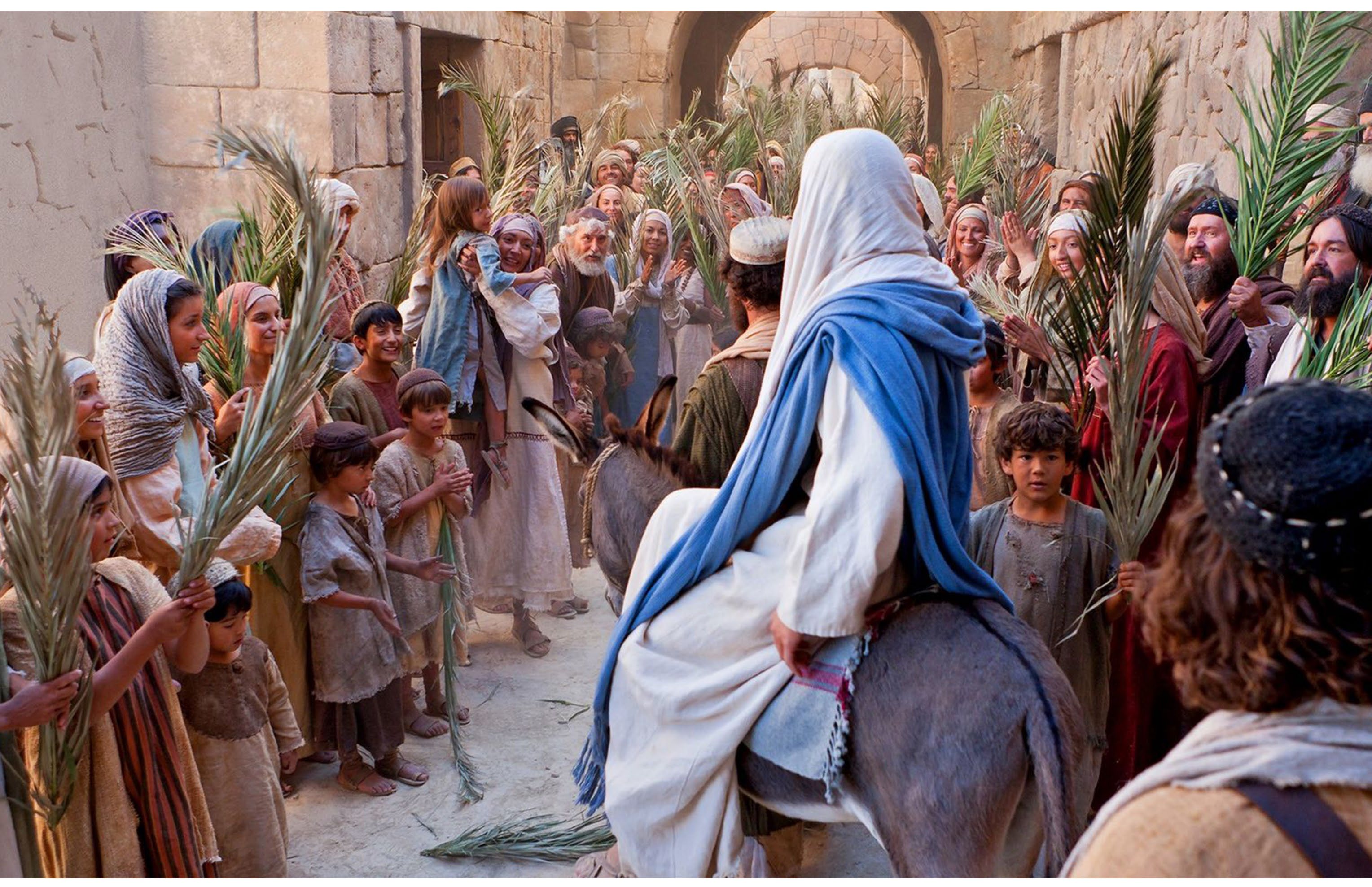Jesus riding into Jerusalem on a donkey, crowds waving palm branches